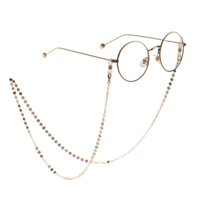 Lunettes rondes dorées avec longue chaîne à disques métalliques sur fond blanc