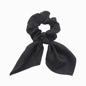 Detail of a black fabric scrunchie with bunny ear bow design on white background