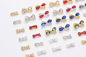 Dettaglio di fiocchi per nail art in lega con perle e strass colorati in finitura oro e argento
