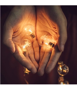 Close-up of LED snowflake fairy lights in warm white glass globes held in hands