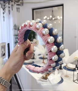 Detailed close-up of double-layer velvet headband with large pearls in pink and blue