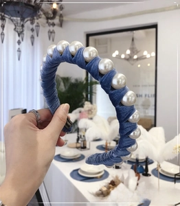 Detail view of large white pearls on a blue velvet headband with a soft texture