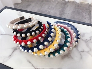 Detail shot of pleated velvet headbands set with large pearls in assorted colors