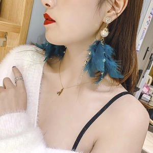 Detail of long tassel earring with deep blue feathers, white pearls, and rhinestones