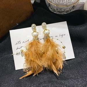 Detailed shot of long caramel feather earrings with pearls and rhinestones decoration