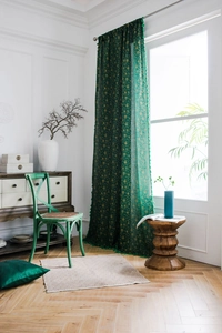 Detail of dark green curtain with gold patterns and tassels in a French vintage room