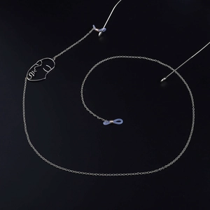 Silver metal eyewear chain with minimalist face pendant on a black background