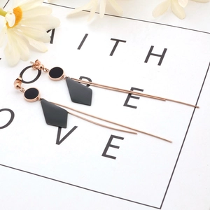 Long rose gold tassel earrings with black geometric rhombus pendants on faith card
