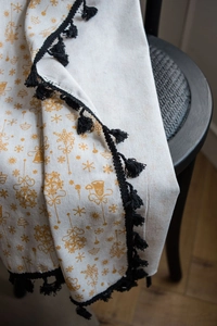 Detail of off-white Christmas curtain fabric with gold snowflake and pom-pom trim