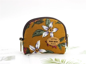 Close-up of ginger yellow cotton coin purse with lily patterns and brown zipper