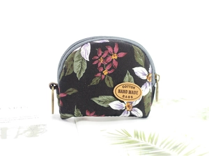 Macro view of semicircular canvas coin purse with floral print and leather logo tag