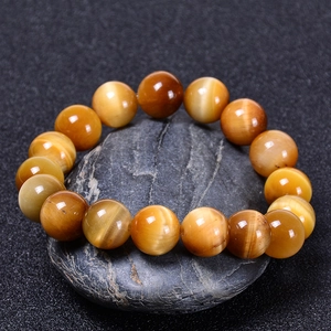 Dettaglio delle perle del bracciale in occhio di tigre dorato su fondo in roccia nera