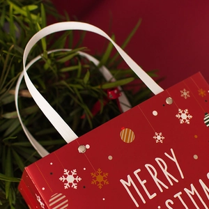 Red Christmas gift bag with white rivet handles and snowflake festive patterns