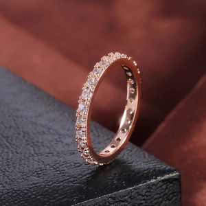Gros plan d'une bague d'éternité en or rose avec pierres étincelantes sur boîte noire