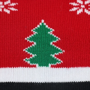 Close-up of winter knit beanie showing festive green Christmas tree pattern on red yarn