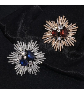 Detailed macro of vintage starburst brooches with crystals on black satin fabric
