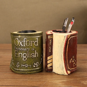 Detail view of retro pen holders shaped like Oxford dictionaries on a wooden desk