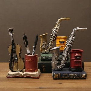 Vintage resin musical instrument pen holders featuring violin and saxophone on book base