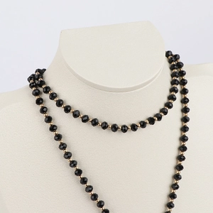 Elegant black faceted beads and gold metal spacers on a beige neck display stand