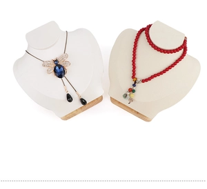 Macro view of velvet necklace bust display with wooden base showing jewelry details