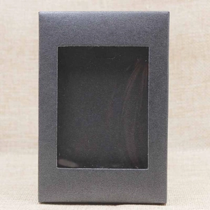 Detailed view of a black cardboard gift box with a transparent PVC window on beige fabric