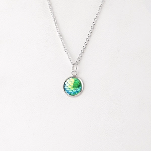 Detailed macro view of 12mm silver pendant with vibrant green and blue ocean scale pattern