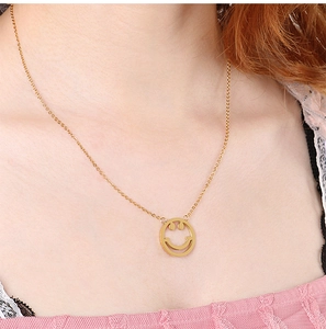 Gros plan d'un collier doré délicat avec un pendentif rond minimaliste en forme de sourire