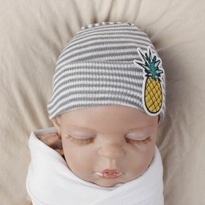 Close-up of baby knit hat with gray stripes and yellow pineapple embroidery detail