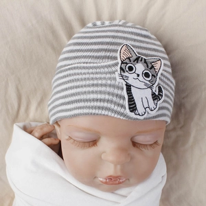 Close-up of baby knit beanie with gray and white stripes and cartoon cat embroidery