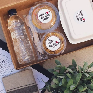 Self-adhesive white thank you for your order stickers on a food delivery package