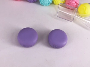 Detail of two macaron-shaped purple plastic cosmetic jars for cream or lip gloss