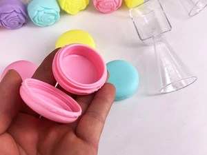 Pink macaron shaped cosmetic jar being opened to show the interior storage space