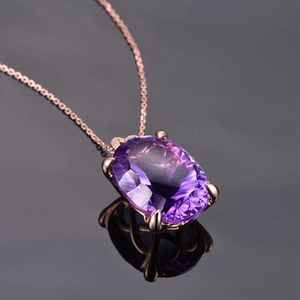 Macro shot of rose gold necklace with oval purple gemstone pendant and subtle reflection