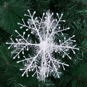 Close-up of a 3D white plastic snowflake ornament with silver tinsel on a pine tree