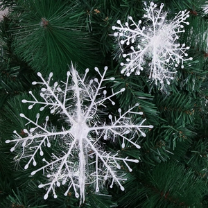 White glitter snowflake ornaments hanging on a green Christmas tree for festive decor