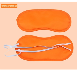Detail view of orange silk-like sleep mask with elastic strap and stitching detail