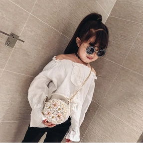 Detail of white round girls' crossbody bag featuring pearls and 3D floral accents