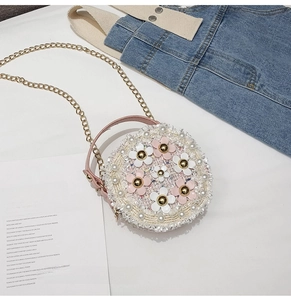 Close-up of cute children's round crossbody bag with pearl and flower details