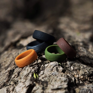 Five assorted colors of 8.7mm bark textured silicone rings for men in outdoor setting