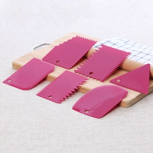 Detailed set of six rose red plastic cake scrapers with varied serrated edges on wood