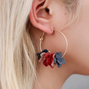 Close-up of gold hoop earrings with colorful fabric petals worn by a model