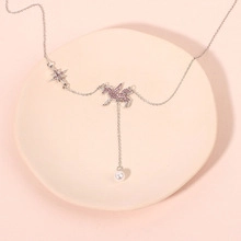 Detailed view of silver necklace with unicorn, star, and pearl charms on a ceramic plate