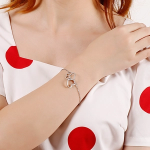 Bracelet chaîne en argent avec breloques patte et cœur porté au poignet d'une femme