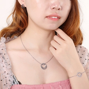 Parure bijoux en acier titane avec motif sourire incluant collier, bracelet et boucles