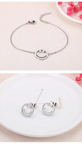 Détail de la parure bijoux sourire argentée avec bracelet et boucles sur une assiette blanche
