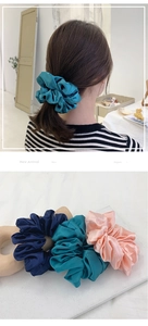 Detail of elegant satin silk scrunchies in navy, peacock blue, and pink colors