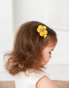 Detail of yellow corduroy flower hair clip on child model for fresh natural look