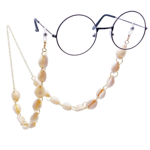 Detailed view of cream shell beads and gold metal chain on a black glasses frame