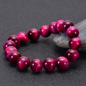 Close-up of rose red tiger eye stone beaded bracelet with natural fiber texture on dark background