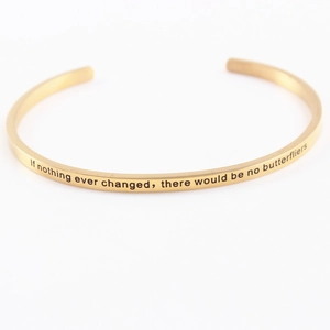 Detailed shot of golden stainless steel bracelet with engraved inspirational mantra text